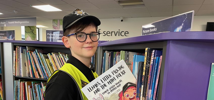 Member of mini police placing book onto shelf