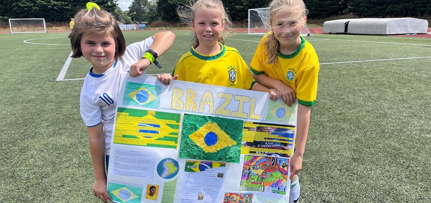 Three pupils from Torfaen holding a poster depicting information about Brazil