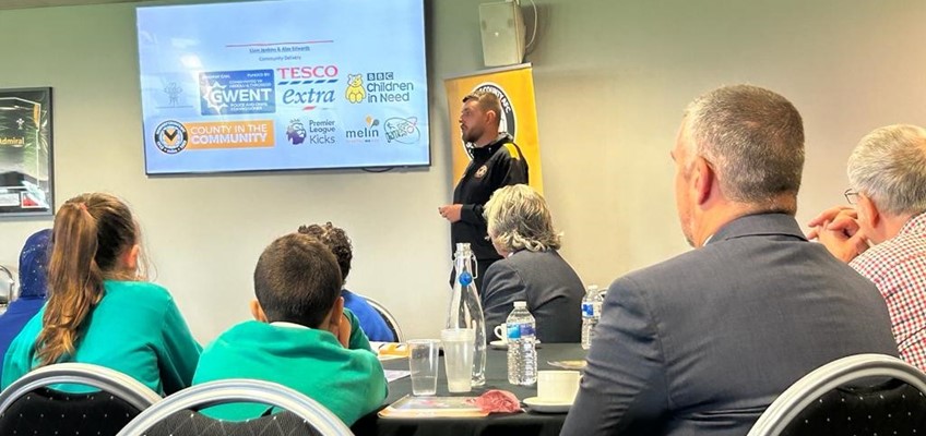 Cynrychiolydd o Sir yn y Gymuned yn cyflwyno i'r gynulleidfa