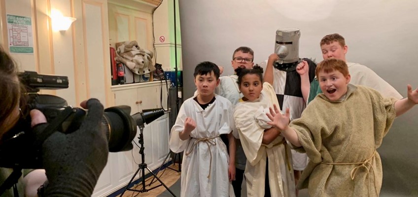 Children dressed as medieval knights being film by someone on camera 