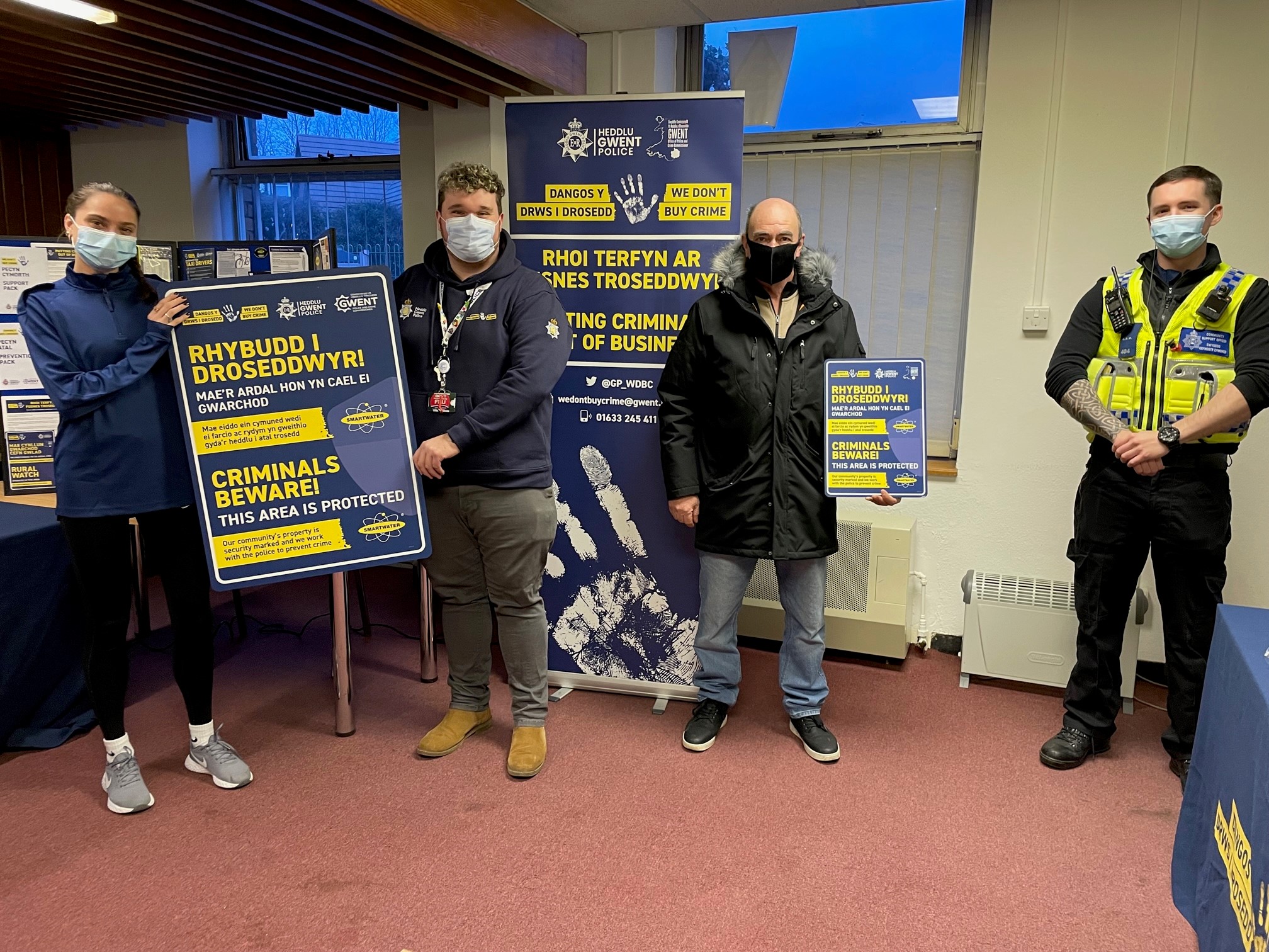 People in room holding we don't buy crime signs