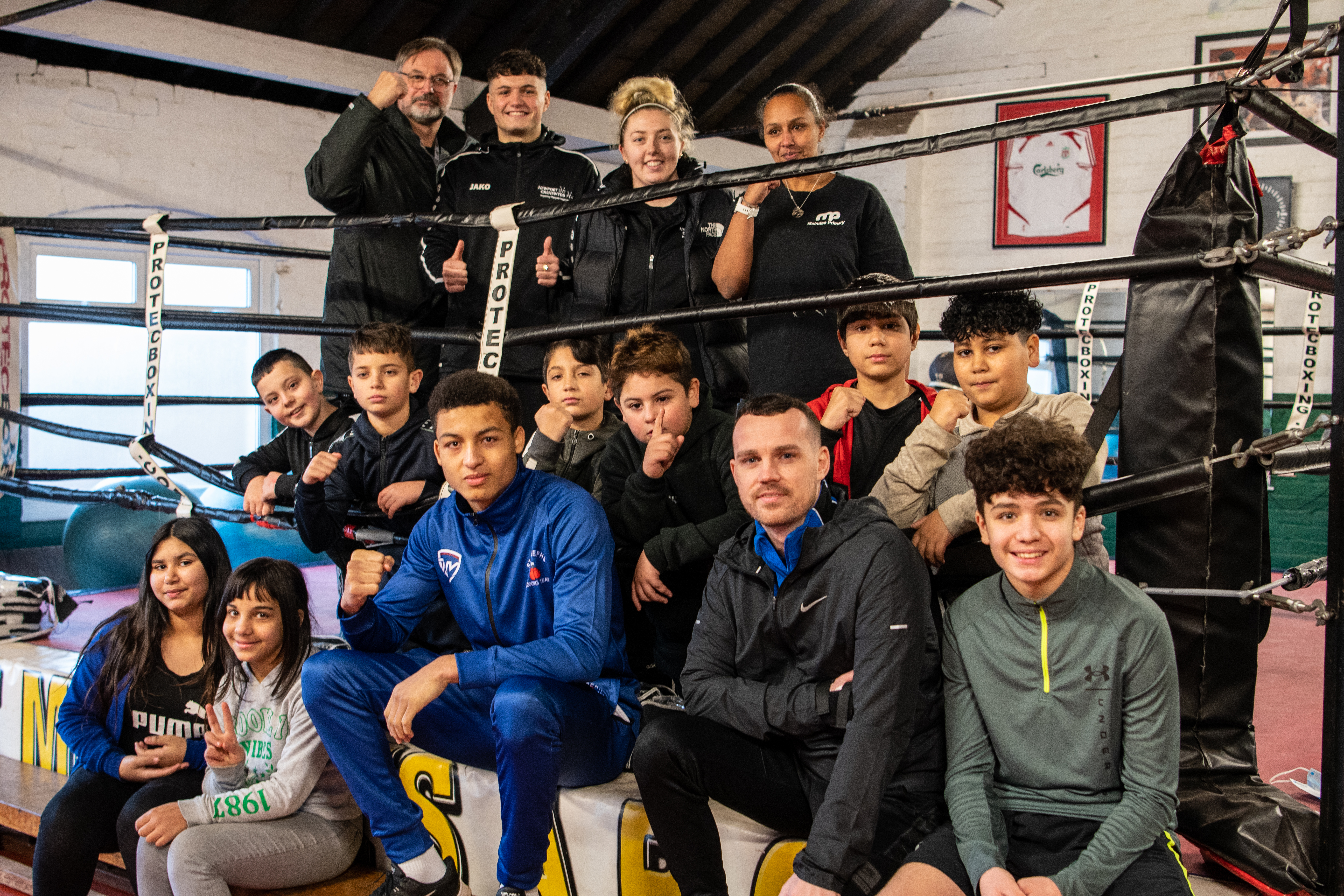Group of children and staff sitting on edge of boxing ring