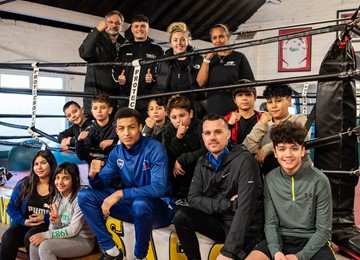 Group of children and staff sitting on edge of boxing ring