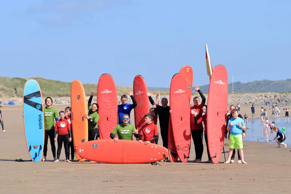 Children on a beach holding surf boards