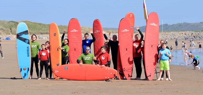 Children on a beach holding surf boards