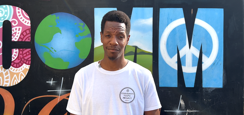 community youth project staff member stood against graffiti backdrop