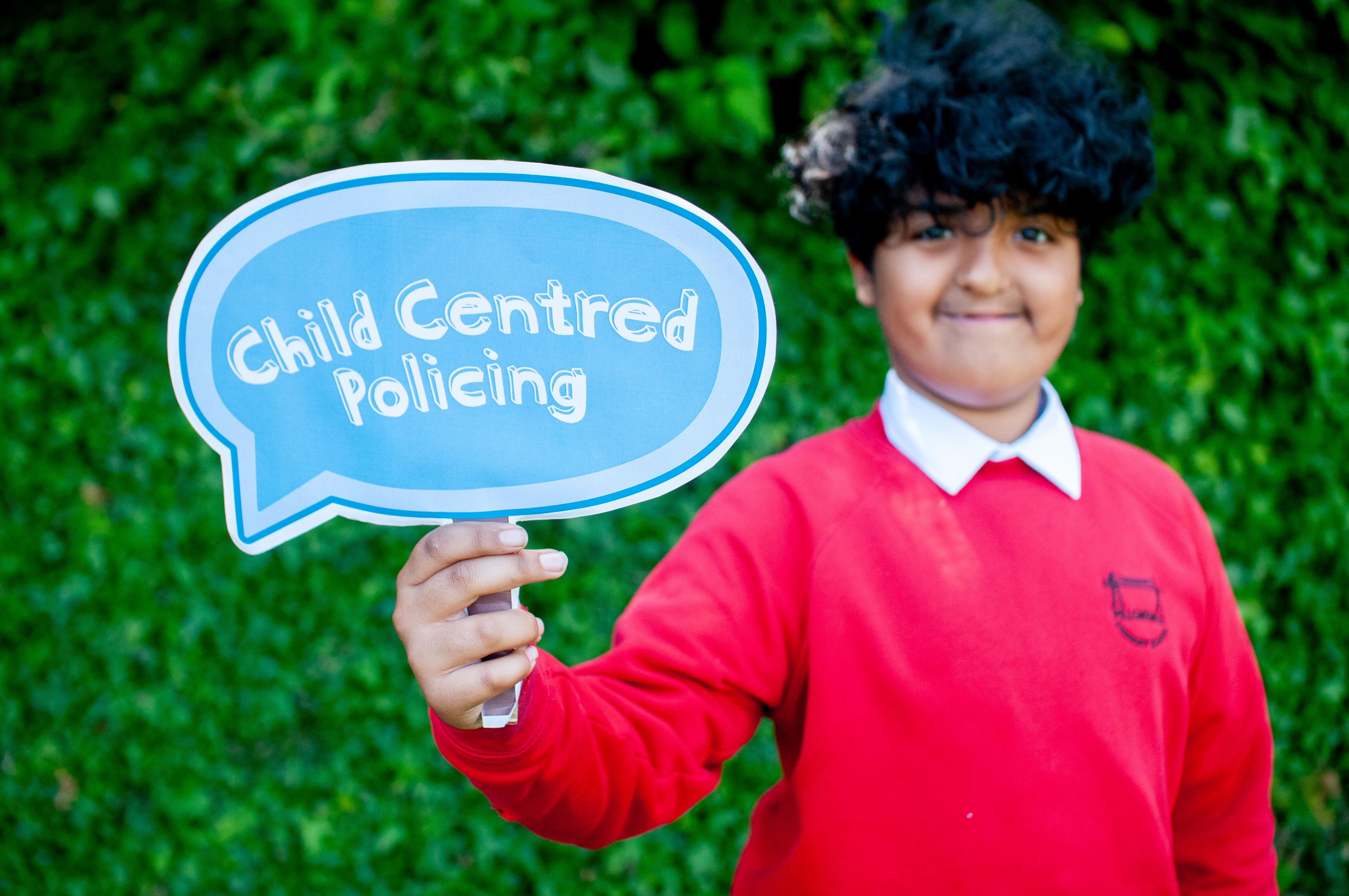 Boy holding Child Centred Policing sign