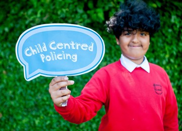 Boy holding Child Centred Policing sign