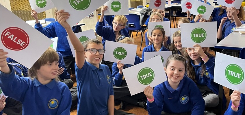 Children answering questions by holding up cards with a tick or cross on