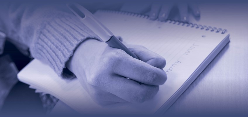 hand with pen writing on note pad